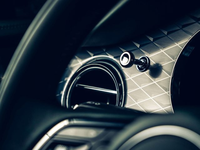 Een close-up van het stuur en de airconditioningopening van een Bentley Bentayga met een luxueus interieurontwerp.