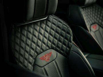 Luxe Bentley Bentayga-interieur met diamantgestikte lederen stoelen en een merklogo in reliëf op de hoofdsteun.