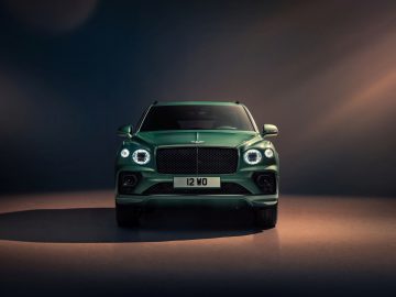 Een groene Bentley Bentayga luxe SUV, gecentreerd onder dramatische verlichting tegen een donkere achtergrond.