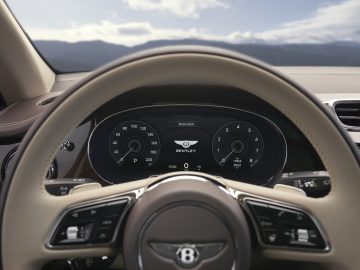 Luxe auto-interieur met een focus op het stuur en het digitale dashboard van een Bentley Bentayga-voertuig.