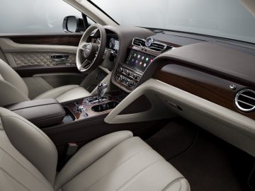Luxe Bentley Bentayga-interieur met lederen stoelen, houten lambrisering en geavanceerde dashboardbediening.