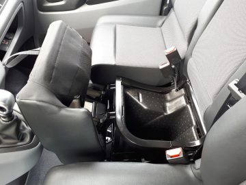 Interieur van een Opel Vivaro met een open opbergvak onder een stoel met zichtbare veiligheidsgordels.