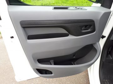 Binnenpaneel van de Opel Vivaro-deur met een handgreep, bedieningsknoppen en opbergvakken.