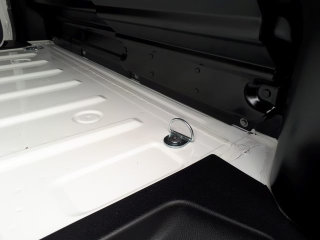 Binnenaanzicht van een Opel Vivaro-kofferbak met een metalen bevestigingslus en de gestructureerde vloer.