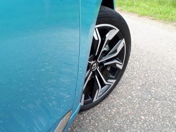 De band van een Renault Clio E-Tech Hybrid lek met zichtbare schade aan de zijwand, geparkeerd langs de kant van de weg waar grind en gras zichtbaar zijn.