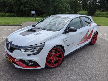 Witte Renault Mégane Trophy-R sportwagen met rode accenten en buiten geparkeerde wielen.