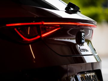 Close-up van de achterkant van een bruine Seat Leon met opvallende achterlichten en modelbadge, die het strakke ontwerp benadrukken.