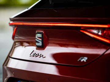 Close-up van de achterkant van een rode Seat Leon met 'leon fr'-embleem en opvallend achterlichtontwerp.