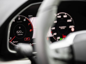 Close-up van het digitale dashboard van een Seat Leon met de snelheidsmeter en toerenteller met een wazig stuur op de voorgrond.