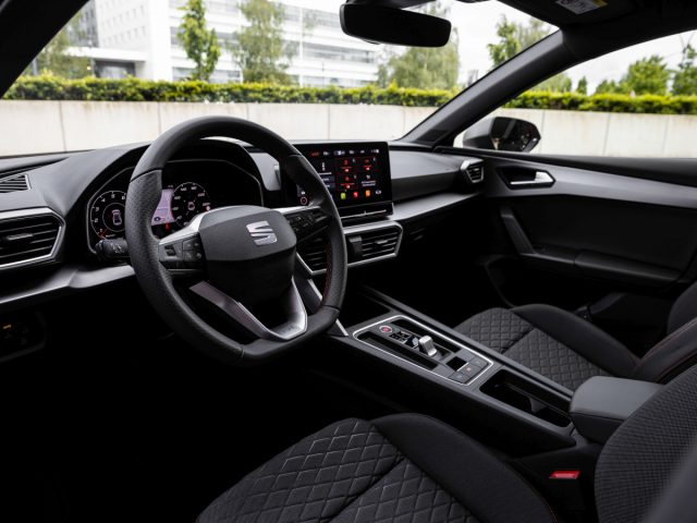 Binnenaanzicht van een Seat Leon met het stuur, het dashboard en de middenconsole met digitale displays.