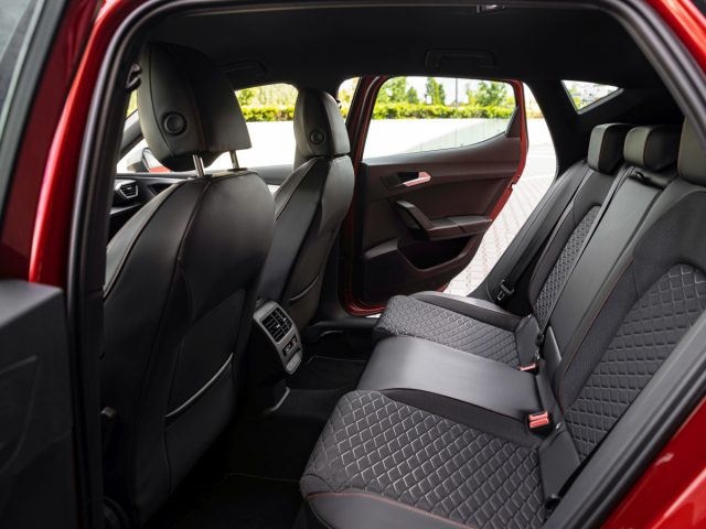 Binnenaanzicht van een Seat Leon met open achterdeuren met rood en zwart gewatteerde lederen stoelen.