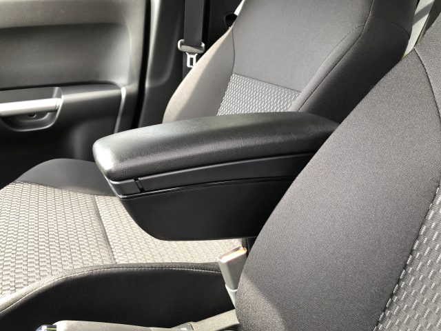 Gesloten middenconsole in een Suzuki Ignis Smart Hybrid tussen de voorstoelen, bekleed met zwarte en grijze stof.