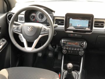 Interieur van een Suzuki Ignis Smart Hybrid met het stuur met logo, dashboard, versnellingspook en navigatiescherm.
