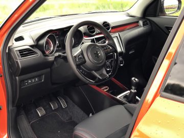 Binnenaanzicht van een Suzuki Swift Sport met het stuur, het dashboard en de handmatige versnellingspook.