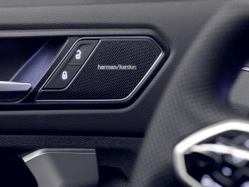 Close-up van het interieur van een Volkswagen Tiguan, met de luidsprekergrille van het Harman/Kardon-audiosysteem.