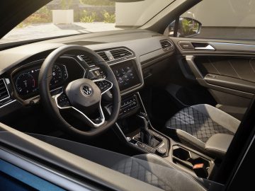 Modern Volkswagen Tiguan-interieur met stuur, dashboard en infotainmentsysteem.