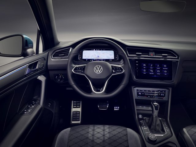 Modern Volkswagen Tiguan-interieur met digitaal dashboard en touchscreens op de middenconsole, voorzien van een stuur met het Volkswagen-logo.