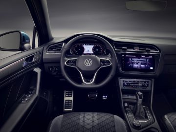 Binnenaanzicht van een Volkswagen Tiguan met het stuur, het dashboard en de digitale displays 's nachts.