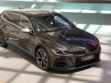 Een Volkswagen Arteon R-Line-auto tentoongesteld in een showroom onder fel licht.