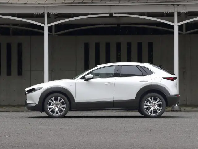 Een witte Mazda CX-30 SUV, buiten geparkeerd onder een afdak, met een modern ontwerp met strakke lijnen en lichtmetalen velgen.