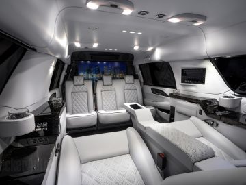 Interieur van een op maat gemaakte Cadillac-limousine met zachte witte lederen stoelen, een minibar, sfeerverlichting en een multimediasysteem.