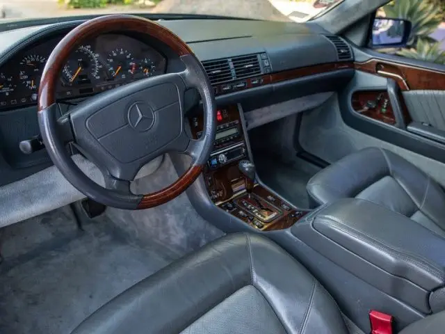 Interieur van een klassieke Mercedes-Benz, met gedetailleerd dashboard, stuur en lederen stoelen.