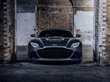 Een zwarte Aston Martin 007 Edition-sportwagen geparkeerd in een slecht verlichte bakstenen boog.