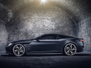 Een strakke zwarte Aston Martin 007 Edition geparkeerd in een slecht verlichte bakstenen tunnel.