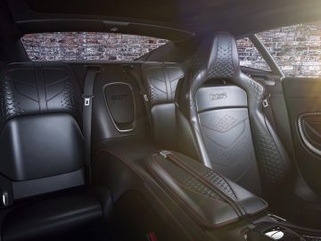 Binnenaanzicht van een Aston Martin 007 Edition-auto, met gedetailleerde leren stoelen en moderne designelementen, met sfeerverlichting.