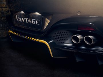 Achteraanzicht van een zwarte Aston Martin 007 Edition Vantage met de uitlaat en het modelnaamplaatje, gemarkeerd door sfeerverlichting.