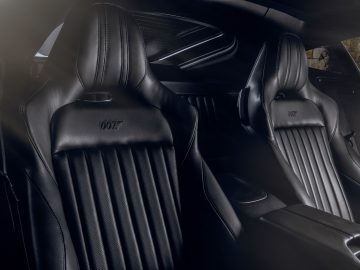 Interieur van een Aston Martin 007 Edition-auto met zwartleren stoelen met het "007"-logo in reliëf op de hoofdsteunen.