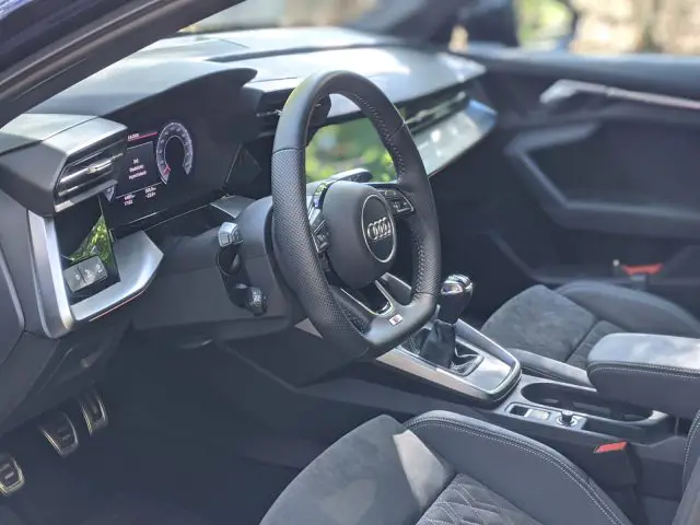 Binnenaanzicht van een Audi A3 met het stuur, het dashboard en de versnellingspook, met de nadruk op de bestuurderszijde.