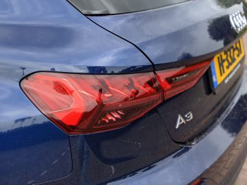 Close-up van het achterlicht en de kofferbak van een blauwe Audi A3, met zichtbaar een Brits kenteken.