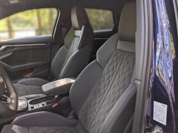 Interieur van een Audi A3 met luxe lederen stoelen, een middenconsole en een open bestuurdersdeur.