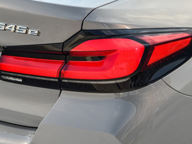 Close-up van de achterkant van een zilveren BMW 545e xDrive-auto met de focus op het rode achterlicht en het modelbadge.
