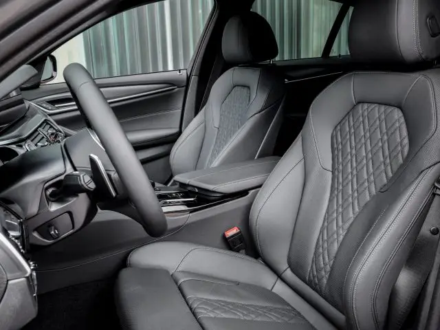 Interieur van een BMW 545e xDrive met luxe zwartleren stoelen, een gedetailleerd dashboard en een strakke middenconsole.