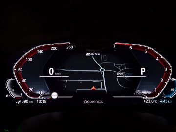 Digitaal dashboard van een BMW 545e xDrive met snelheidsmeter, navigatiekaart, brandstofmeter en verschillende statusindicatoren 's nachts.