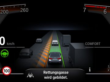 Digitaal autodashboard van de BMW 545e xDrive met een snelheidsmeter, een versnellingsindicator, een brandstofmeter en een groen pictogram dat adaptieve cruisecontrol aangeeft. Er wordt gewaarschuwd voor het vormen van een noodcorridor