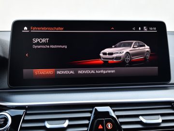 Auto-infotainmentscherm in een BMW 545e xDrive met sportmodusopties met een digitaal beeld van een auto, in een dashboard.