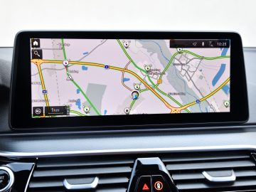 In-car navigatiesysteem dat een kaart met verschillende GPS-routes weergeeft op een digitaal touchscreen in een BMW 545e xDrive.
