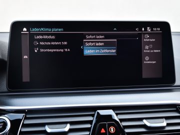 Het infotainmentsysteemscherm van de BMW 545e xDrive met oplaadinstellingen in het Duits, met opties voor onmiddellijk of gepland opladen.