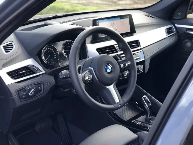Binnenaanzicht van een BMW X1 xDrive25i-auto met het stuur, het dashboard en het multimediasysteem.