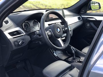 Binnenaanzicht van een BMW X1 xDrive25i met het stuur, het dashboard en de voorstoelen.