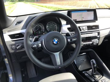 Binnenaanzicht van een BMW X1 xDrive25i met de nadruk op het stuur, het dashboard en de middenconsole met een navigatiedisplay.