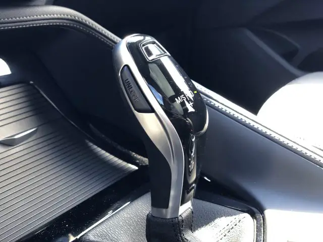 Automatische versnellingspook in het interieur van een BMW X1 xDrive25i, met chromen en zwarte details.