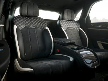 Interieur van een Bentley Bentayga Speed met twee zwartleren stoelen met diamantstiksel, een middenconsole en deurpanelen met koolstofvezelbekleding.
