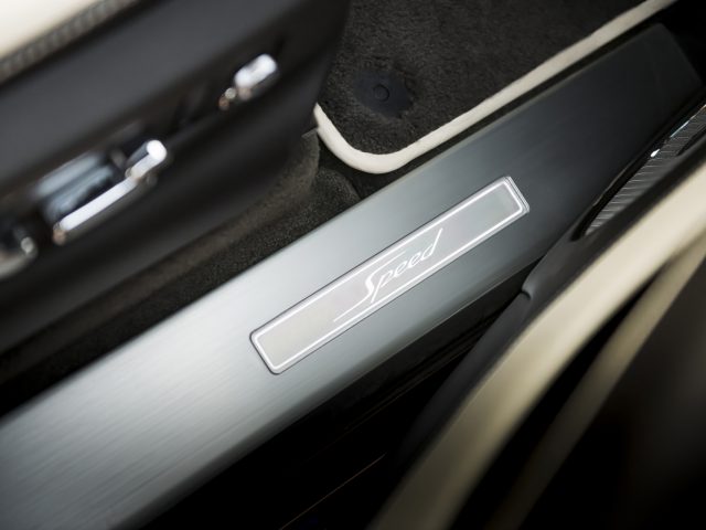 Close-up van de instaplijsten van een Bentley Bentayga Speed met een verlicht 'speed'-logo, met luxe interieurdetails.