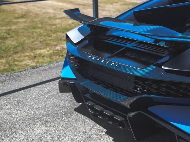 Blauwe Bugatti Divo-sportwagen met een opvallende achterspoiler en gedetailleerd grillontwerp, buiten geparkeerd.