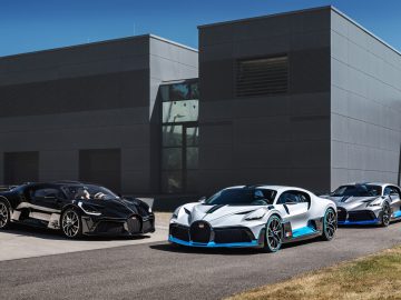 Drie Bugatti Divo-sportwagens geparkeerd voor een modern grijs gebouw met strakke ontwerpen en levendige accentkleuren.