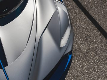 Luchtfoto van een grijze Bugatti Divo-sportwagen met blauwe accenten, geparkeerd, waarbij de strakke motorkap en het grille-ontwerp goed tot hun recht komen.